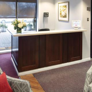 A welcoming reception desk in an office lobby, featuring a vase of flowers and comfortable seating.