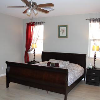 A cozy bedroom with a dark wooden bed, nightstands, and lamps under a ceiling fan.