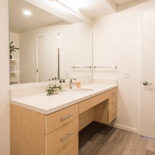 A modern minimalist bathroom with a vanity and large mirror.