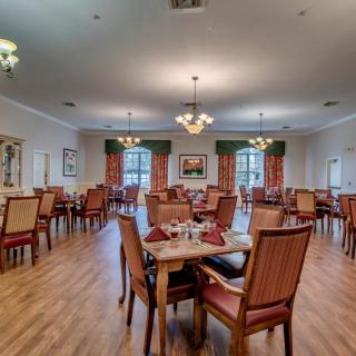 Spacious dining room with elegant chandeliers and wooden flooring.