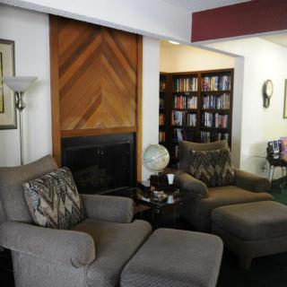 A cozy living room featuring two comfortable chairs, a bookshelf filled with books, and a small globe on the side table.