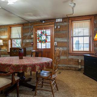 A cozy, rustic dining room with a round table and wooden chairs set against log cabin-style walls.