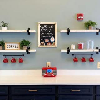 A stylish coffee station with shelves, red mugs, and decorative plants against a light blue wall.
