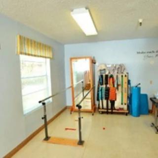 A therapy room equipped with parallel bars and various exercise equipment.