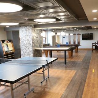 A spacious recreation room featuring ping pong tables and a modern interior design.
