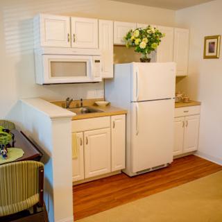 A cozy and modern kitchen featuring white cabinets, a refrigerator, and a microwave.