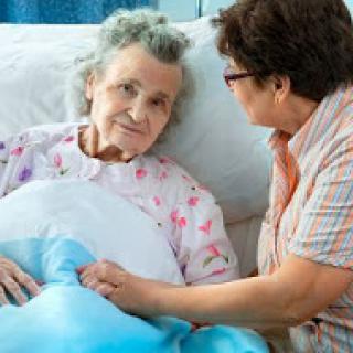 A caregiver shares a moment of comfort with an elderly patient in a hospital setting.