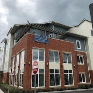 A multi-story building with visible roof damage under an overcast sky.
