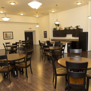 A spacious dining room with wooden tables and chairs, featuring modern lighting and a sleek interior design.