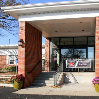 Entrance of a brick building with a banner and potted plants.