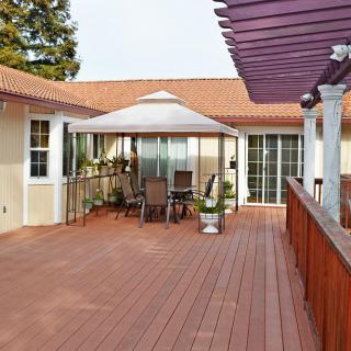 A spacious outdoor deck with wooden flooring, featuring a gazebo and patio furniture.