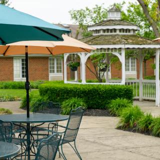 A peaceful outdoor garden area featuring a gazebo, patio furniture, and colorful umbrellas.