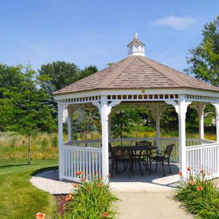 A charming white gazebo in a lush garden setting.