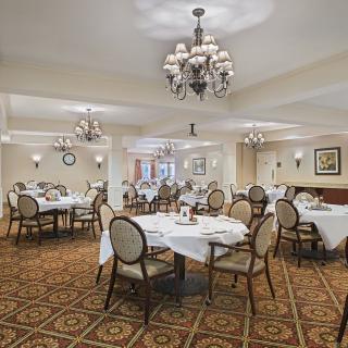 An elegant dining room with chandeliers and neatly arranged tables and chairs.