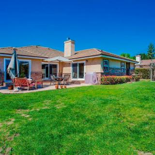 A sunny backyard featuring a spacious patio and well-maintained lawn.