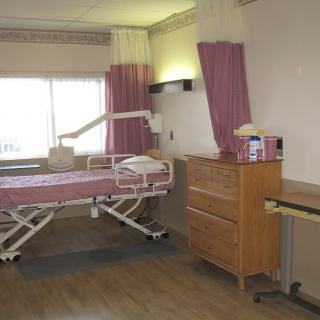 A hospital room equipped with a bed, curtains, and medical furniture.