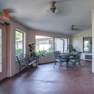A serene indoor patio area featuring tables and chairs, adorned with plants and illuminated by natural light.