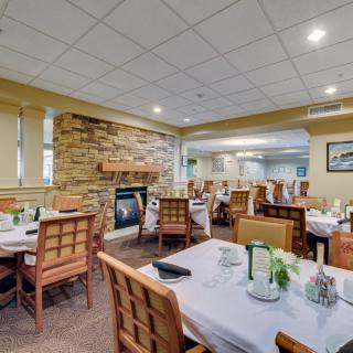 A cozy restaurant dining area with neatly arranged tables and a stone fireplace.