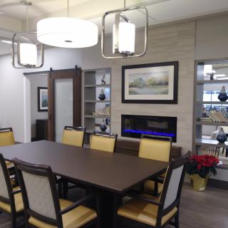 A modern dining room with a large table, surrounded by chairs and adorned with contemporary lighting and wall art.