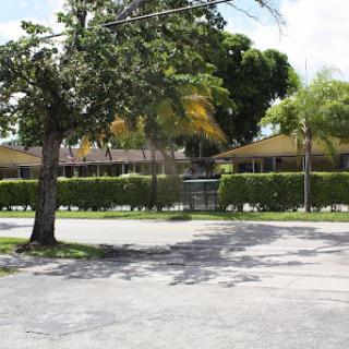 A view of a street corner with residential buildings and lush greenery.