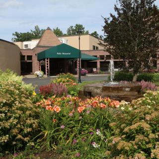A scenic view of a building surrounded by a colorful garden with blooming flowers and trees.