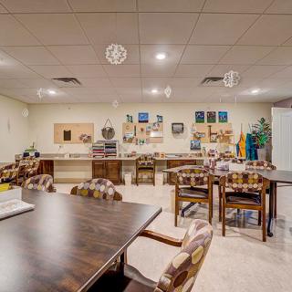 A well-equipped classroom or meeting space with tables, chairs, and various art supplies.