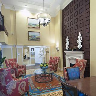 A spacious living room with high ceilings, elegant furniture, and a sophisticated fireplace provides a cozy and stylish atmosphere.