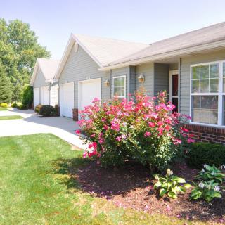 A suburban house with a well-maintained garden and bright pink flowers along the driveway.