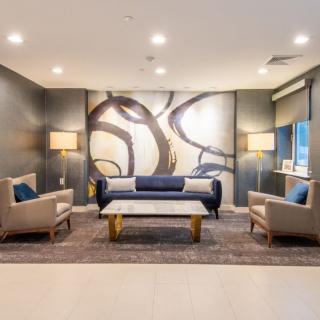 A modern living room featuring a stylish sofa, two chairs, and a coffee table, with contemporary artwork on the wall.