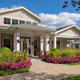 A beautifully landscaped residential building with a colorful garden and clear blue sky.
