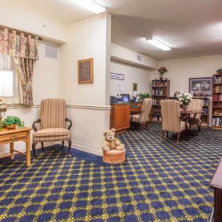 A cozy living room with patterned carpet, armchairs, and bookshelves.