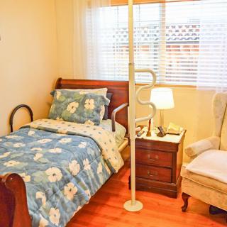 A cozy bedroom with floral bedding, a wooden nightstand, and a comfortable armchair by the window.