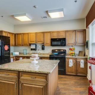 A modern kitchen with wooden cabinets and an island, featuring appliances and bright lighting.