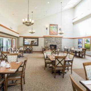 A spacious and elegant dining area with tables, chairs, a fireplace, and large windows.