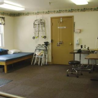 A physical therapy room with exercise equipment and a therapy bed.