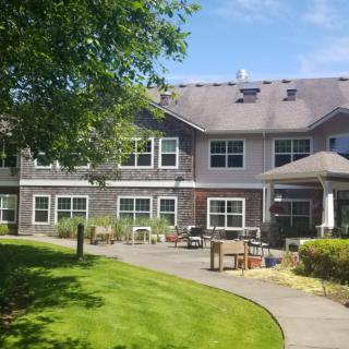 A two-story building with a well-maintained lawn and outdoor seating area.