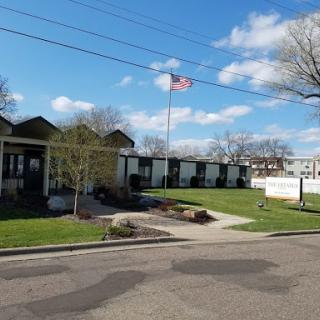 A view of a residential building with an American flag waving in the breeze under a partly cloudy sky.