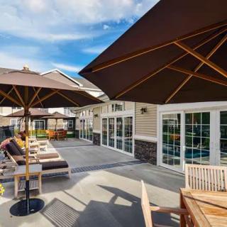 A sunny outdoor patio with lounge chairs and umbrellas on a spacious deck.