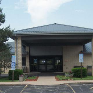 A front view of a building with a parking lot and landscaped surroundings.