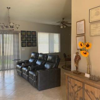 A cozy living room with leather recliners, sunflowers in a vase, and framed certificates on the wall.