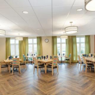 A spacious dining room with round tables, chairs, and elegant lighting.