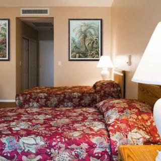 A cozy hotel room with two beds featuring floral bedding and decorative paintings on the wall.