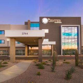 A modern hotel building with a desert landscape at dusk.