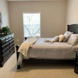 A cozy bedroom with a neatly made bed and dark wooden furniture.