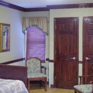 A cozy bedroom featuring wooden doors, a window with blinds, and classic furniture.