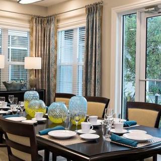 A modern dining room with an elegantly set table, featuring blue glass pitchers and neatly arranged napkins.