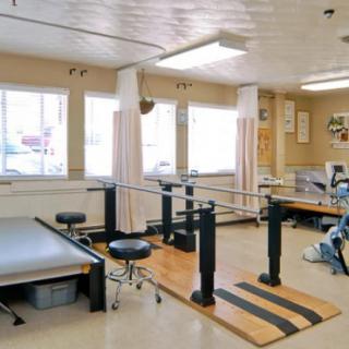 A rehabilitation room equipped with parallel bars and other therapy tools for physical therapy exercises.