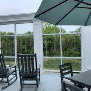 A screened patio with outdoor furniture and a view of trees.