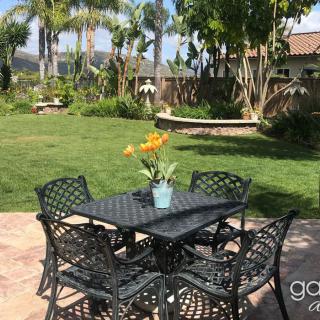 A peaceful garden patio with a metal table and chairs, adorned with a vase of flowers.