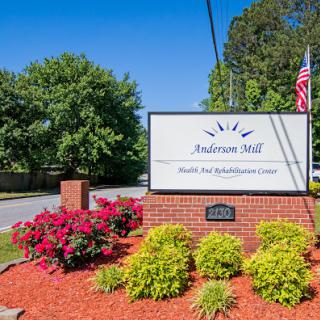 Entrance sign for Anderson Mill Health Care Administrative Center surrounded by vibrant landscaping.